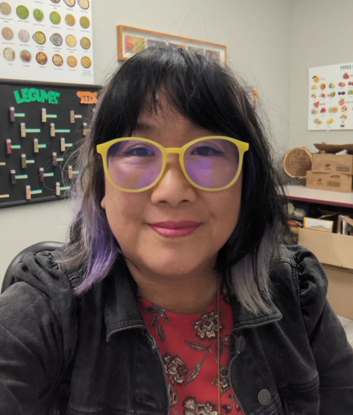 Headshot of Phoebe Lee. She is facing the camera and smiling. In the background, nutrition posters are visible. 